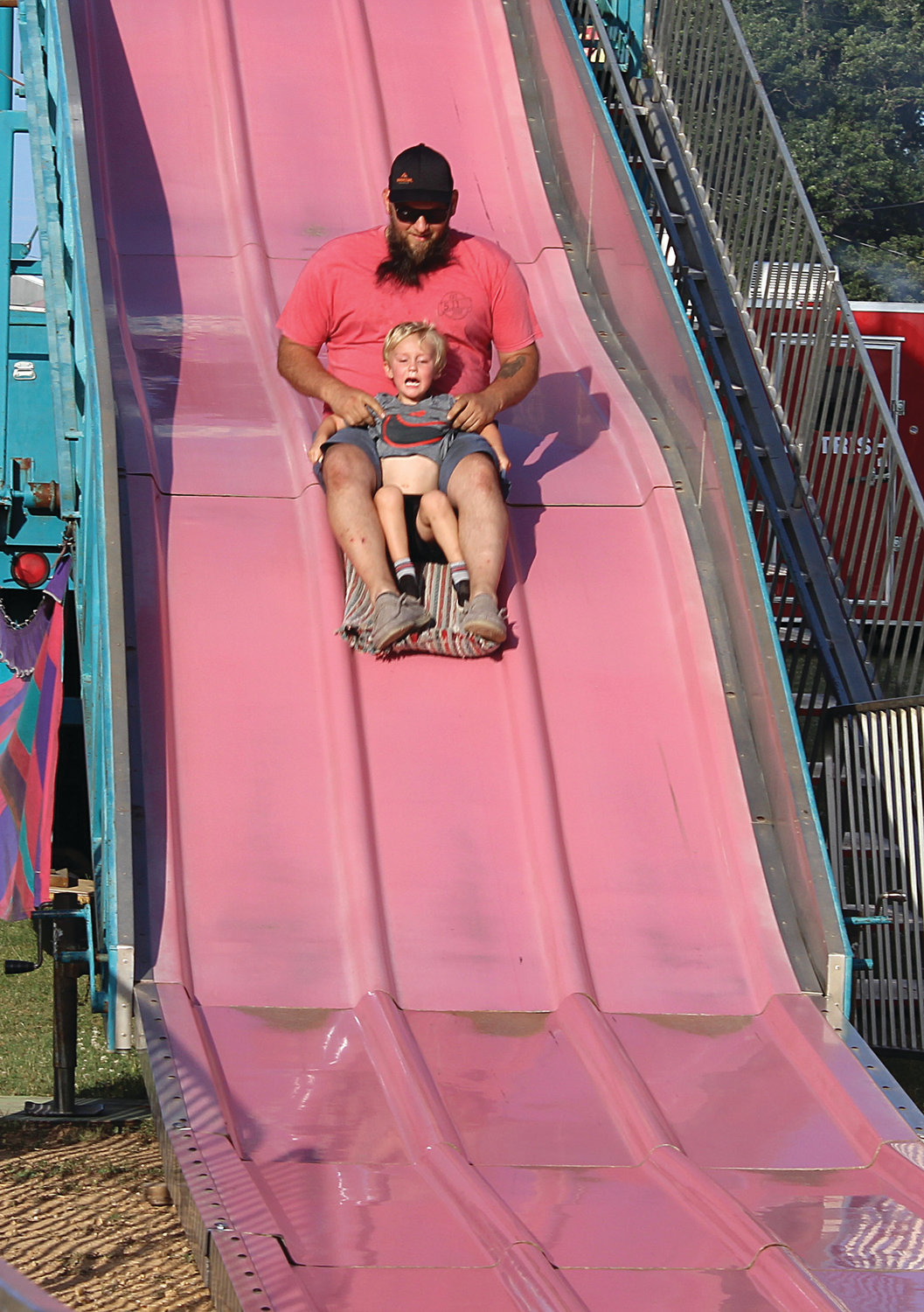 Jarrett Young holds on to a frightened Wyatt Young as they go down the Super Slide during the Tri-County Fair.